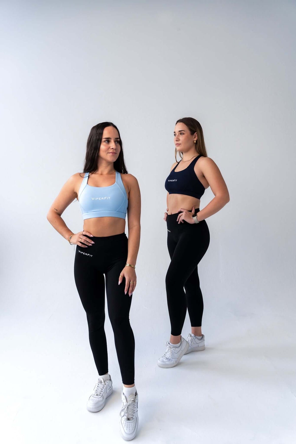 Two models in ViperFit Pulse Scrunch Leggings - Black with sky blue and navy ViperFit pulse sports bras.